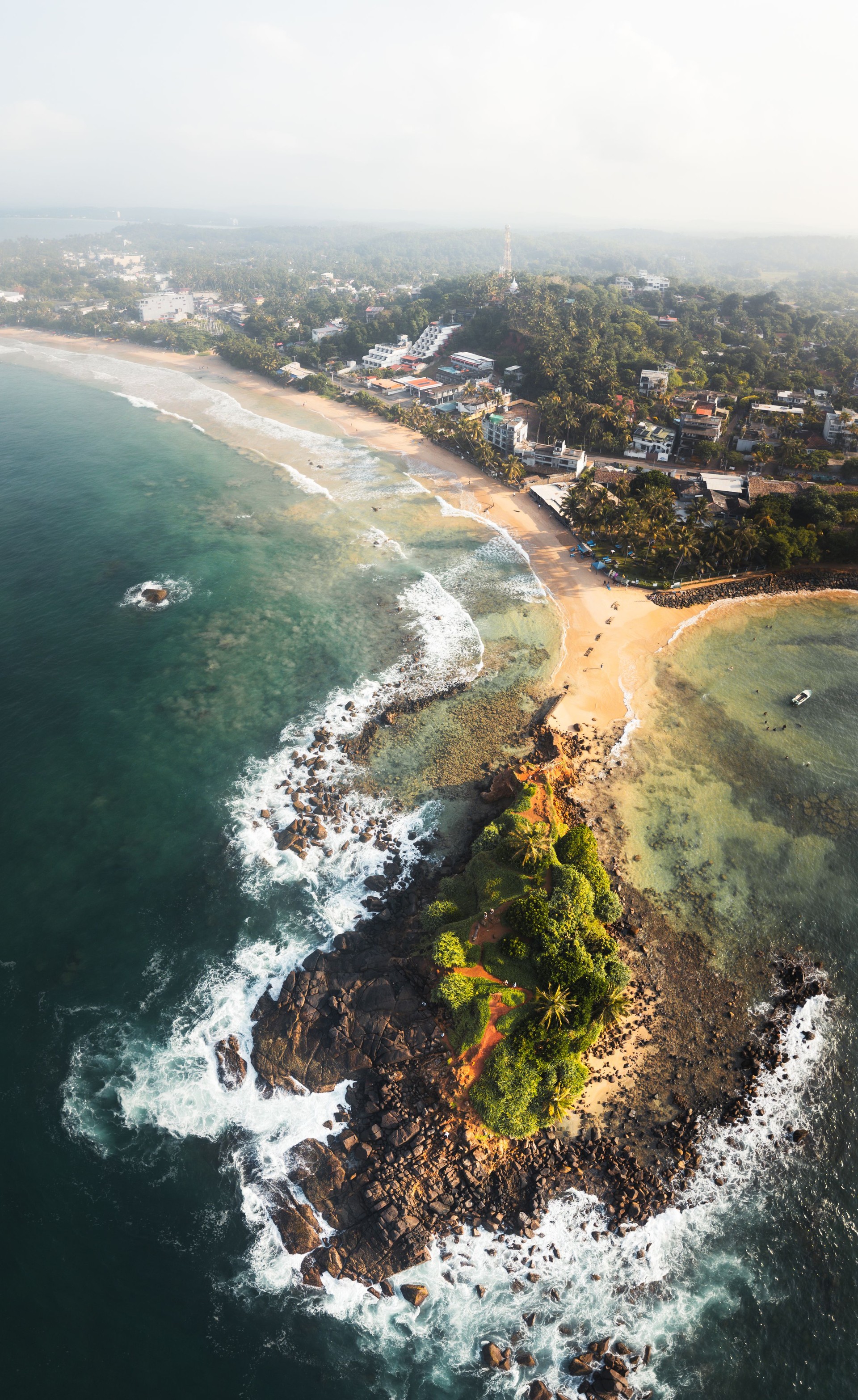 Aerial cinematic revealing view Mirissa coastline in southern Sri Lanka with golden beaches, turquoise waters, and beachfront hotels nestled among swaying palms. Paradise holiday destination in asia