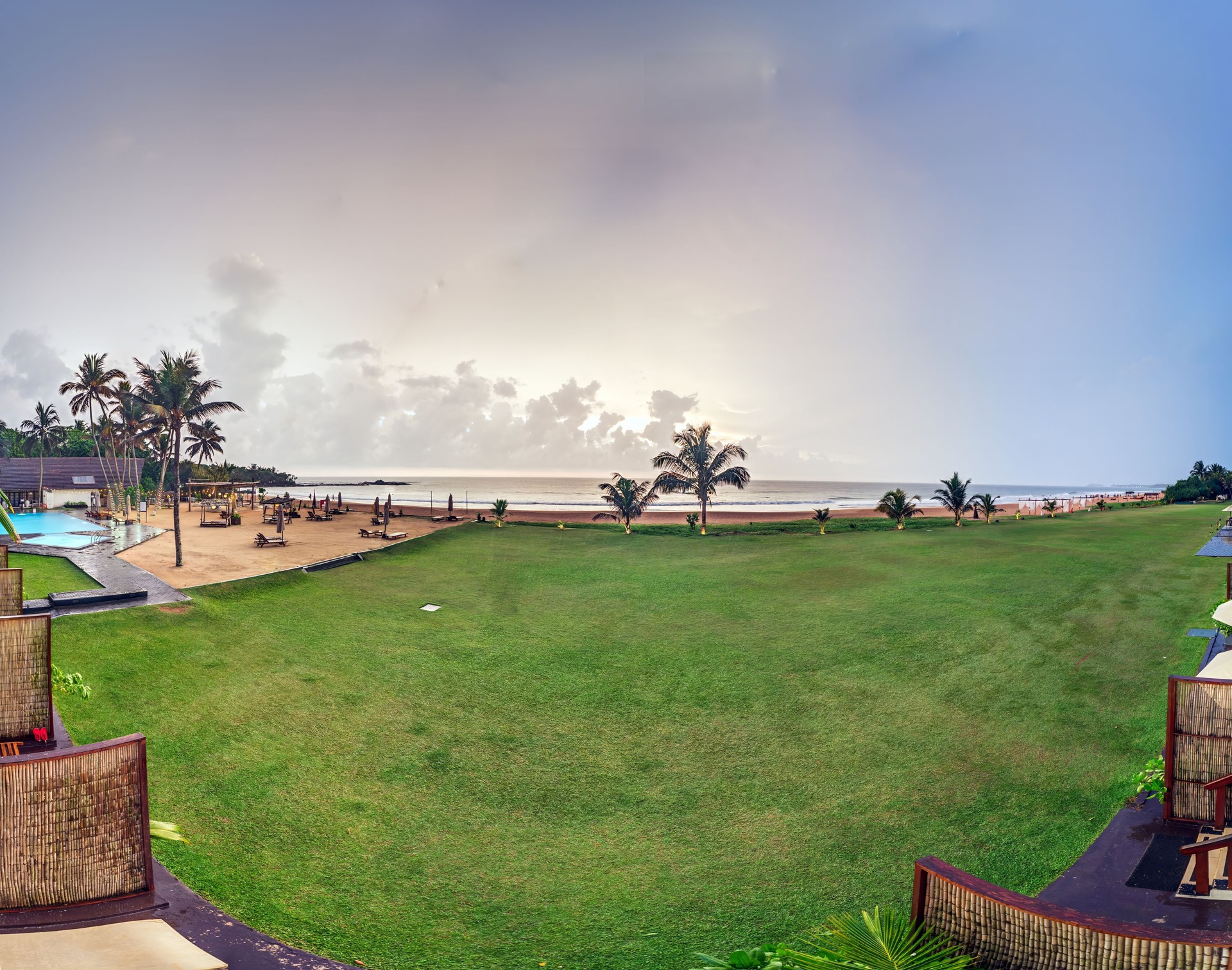Tropical beach resort with palm trees and sunset at the oceanfront